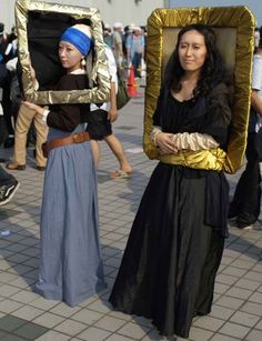 two women in costume holding up pictures with gold frames on their heads and one woman wearing a blue headband