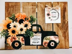 an old truck decorated with flowers is hanging on the wall next to a sign that says home sweet home