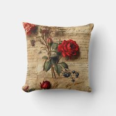 a decorative pillow with red roses on an old sheet of paper, and some berries