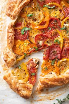 a pizza with tomatoes, cheese and herbs cut into slices on a white tablecloth