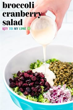 broccoli, cranberry salad in a blue bowl being drizzled with dressing