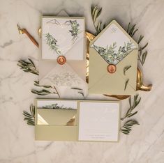 the wedding stationery is laid out on top of the marble table with greenery