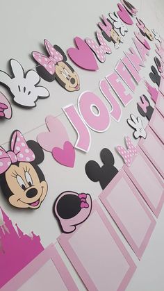 a minnie mouse birthday party banner with pink and black paper cutouts on the wall