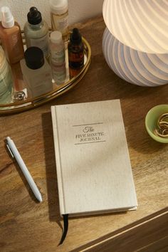 an open book sitting on top of a wooden table next to a cup and pen