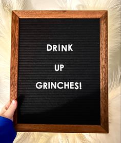 a person holding up a sign that says drink up grinches in front of them