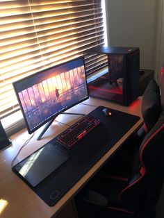 a computer desk with a keyboard, mouse and monitor on it in front of a window