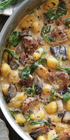 a pot filled with meat, potatoes and spinach on top of a wooden table