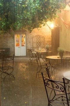 an outdoor cafe with tables and chairs in the rain