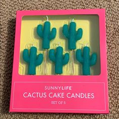 four cactus cake candles in a pink box