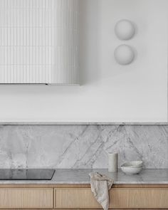 a kitchen with marble counter tops and wooden cabinets in front of a wall mounted oven