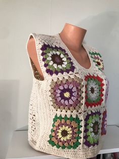 a white crocheted vest with multicolored flowers on it