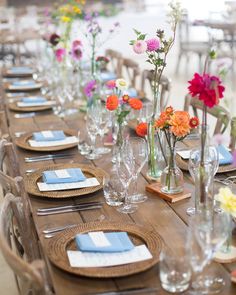 a table set with place settings and flowers in vases