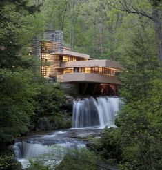 a house in the woods next to a waterfall