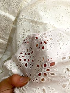 a person is holding something in their left hand while wearing a white dress with red dots on it