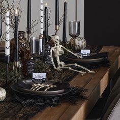 the table is set with candles, skeleton decorations and other halloween decorating items on it