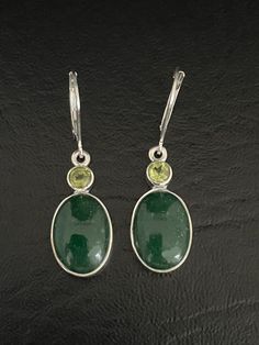 GENUINE NEPHRITE JADE AND PERIDOT EARRINGSNatural and Minimalist Sterling Silver Green Jade and Peridot Dangle Lever-back EarringsBeautifully smooth forest green Nephrite Jade and Peridot are known for having the ability to attract love, luck, and an abundance of wealth!!Metal: .925 Sterling Silver EarringsMEASUREMENT:  Natual Peridot Height:  38.1MM (1.5 inches)Width:  10MM (0.4 Inches)Dangles measure approximately 38.1MM (1.5 inches) from the top of the ear wire to the bottom of the ear wire** Green Oval Earrings With Natural Stones, Oval Green Earrings With Natural Stones, Green Natural Stone Earrings For Wedding, Green Natural Stones Earrings For Wedding, December Birthstone Jewelry, Book Necklace, Bridal Wedding Earrings, Fire Opal Necklace, Sterling Silver Locket