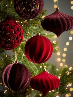 christmas ornaments hanging from a tree with lights in the background