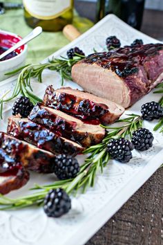 meat and berries on a white platter next to bottles of wine