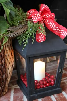 a small black lantern with red balls in it and a white candle on the top