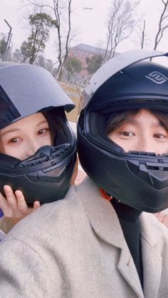 two people with helmets on their heads posing for the camera