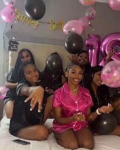 a group of women sitting on top of a bed with balloons in the shape of numbers