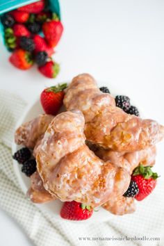 three donuts on a plate with strawberries and blackberries in the back ground