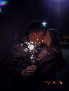 a man and woman kissing while holding sparklers