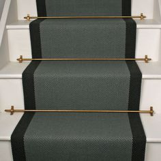 a carpeted stair case with black and white stripes on the bottom, along with gold handles