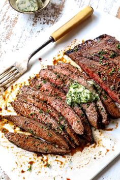 sliced steak on a cutting board next to a knife and fork