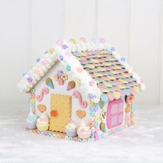 a gingerbread house decorated with icing and sprinkles on a white surface