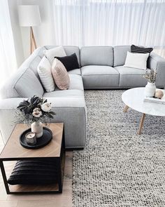 a living room with a gray sectional couch and coffee table in front of a large window