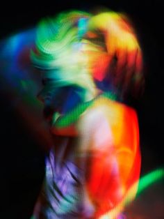 a blurry image of a woman dancing with colored lights on her face and body