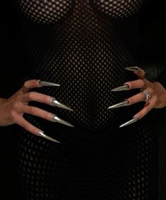 a woman's hands with silver nails and black mesh dress, holding onto her belly