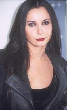 a woman with long black hair wearing a leather jacket