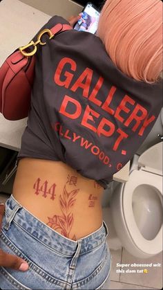 the back of a woman's stomach with tattoos on it and words written in red