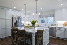 a large kitchen with white cabinets and an island in the middle, surrounded by wooden flooring