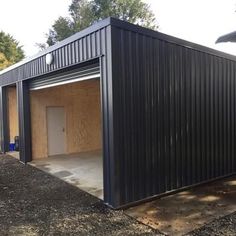 a black metal building sitting on top of a gravel field