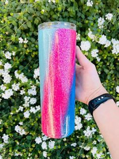 a hand holding a pink and blue glitter tumbler