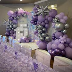 purple and silver balloons are on display in the center of a banquet table set up for an event