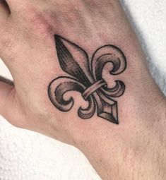 a hand with a tattoo on it and a fleur de lis symbol in the middle