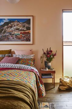 a bedroom with pink walls and colorful bedding