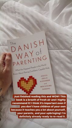 a person laying in bed with a book about the danish way of parenting on it