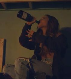 a woman sitting on the floor drinking from a bottle