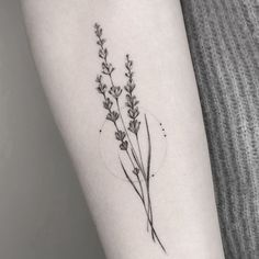 a single flower tattoo on the left inner arm, with small flowers growing out of it