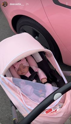 a baby in a pink stroller next to a pink car