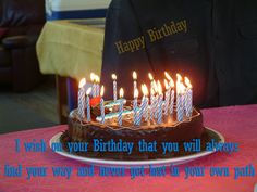 a birthday cake with lit candles on it sitting on a table in front of a person