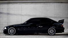 a black car parked in front of a brick wall