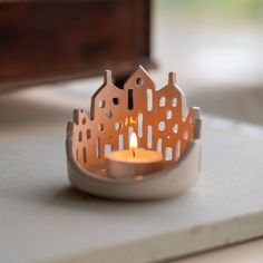 a candle that is sitting on top of a white table with some buildings in the background