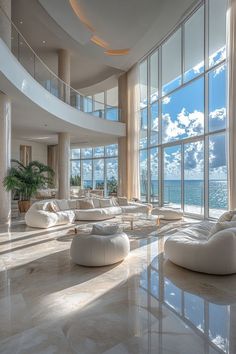 a large living room with lots of windows and white furniture in front of the ocean