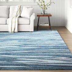 a living room with white furniture and blue rug